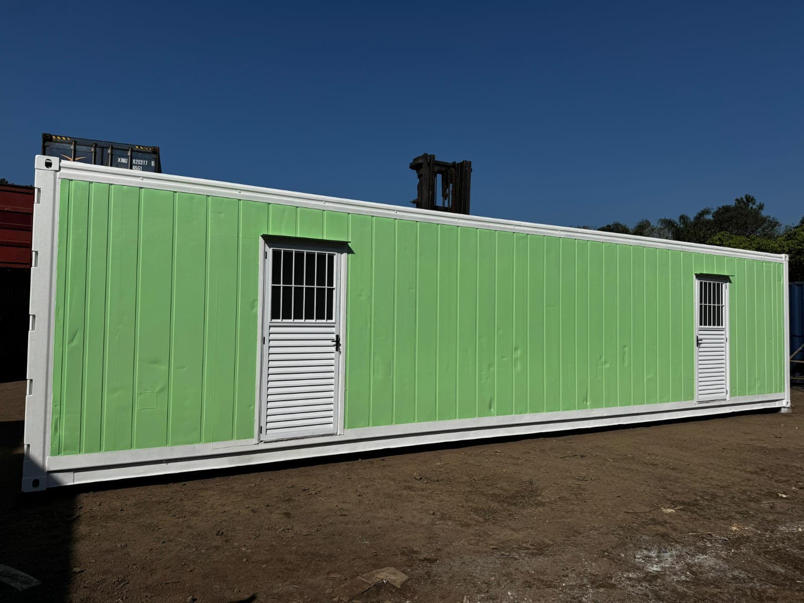 Container habitacional verde instalado em base de concreto